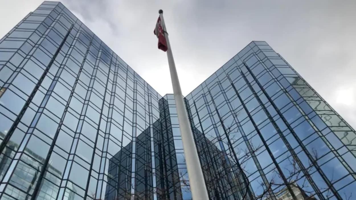 Photo d'un édifice avec, devant, un drapeau du Canada.