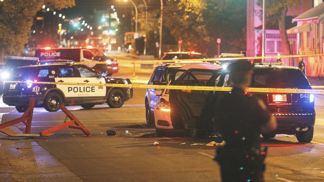 Des véhicules de la police d'Edmonton sont arrêtés au milieu d'une rue, toutes lumières allumées.