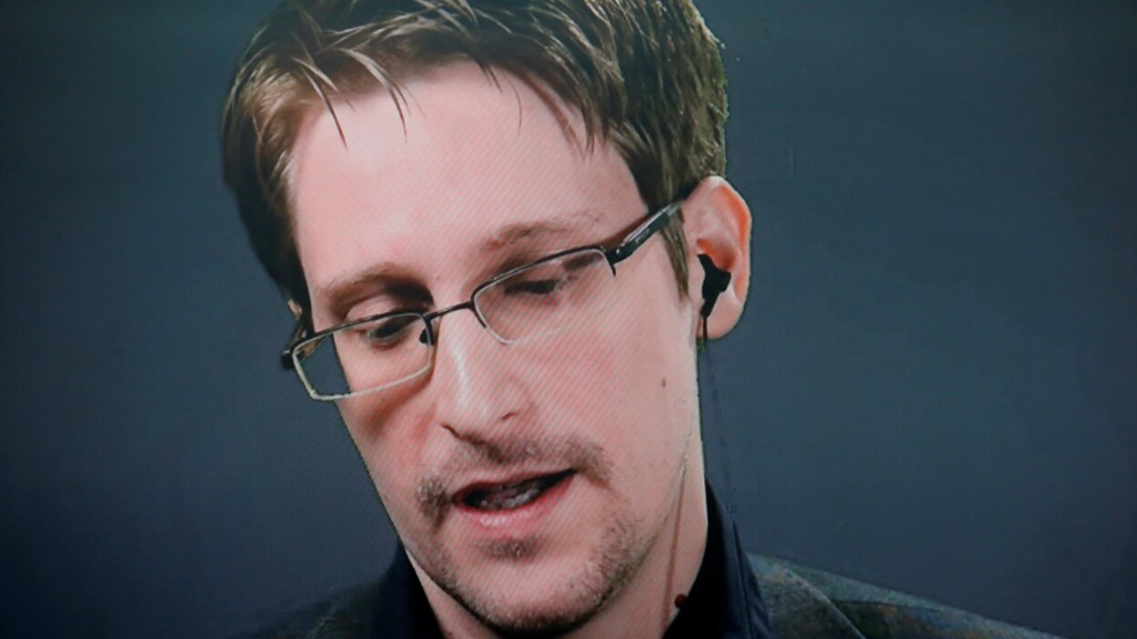 Edward Snowden, portant des lunettes, regardant vers le bas, au cours d'une allocution prononcée par vidéoconférence.