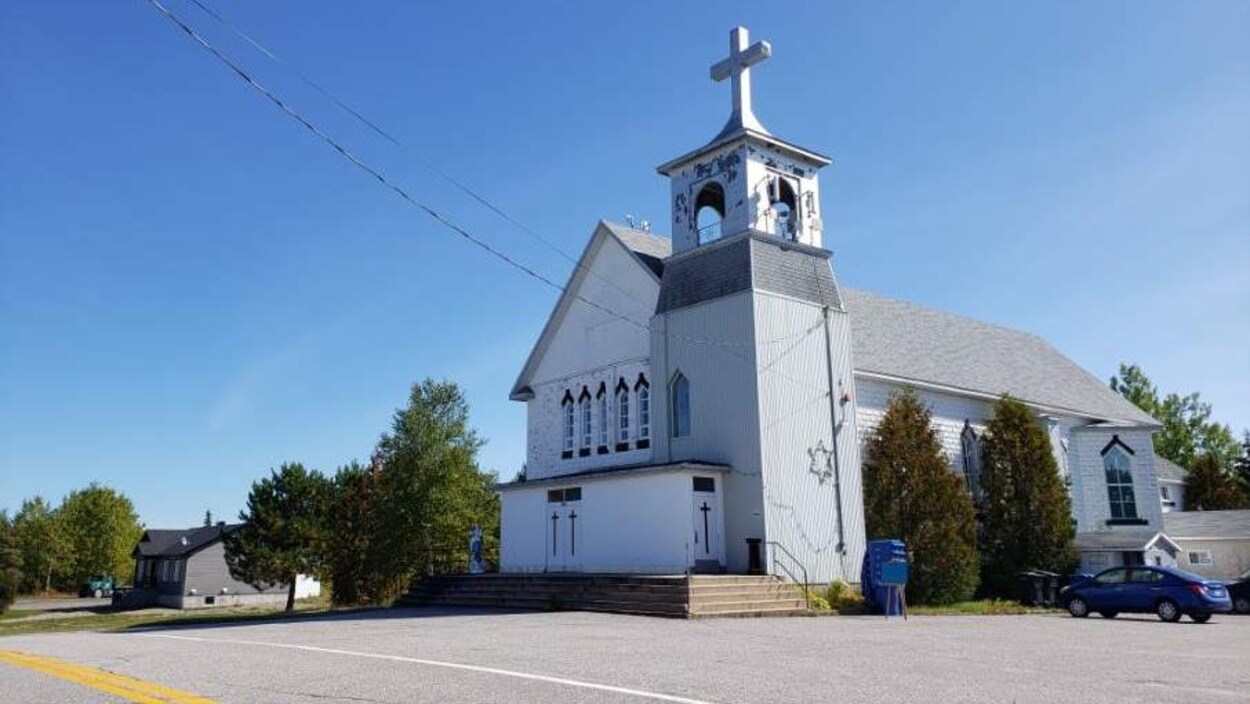 Une église blanche se dresse sous un ciel bleu.