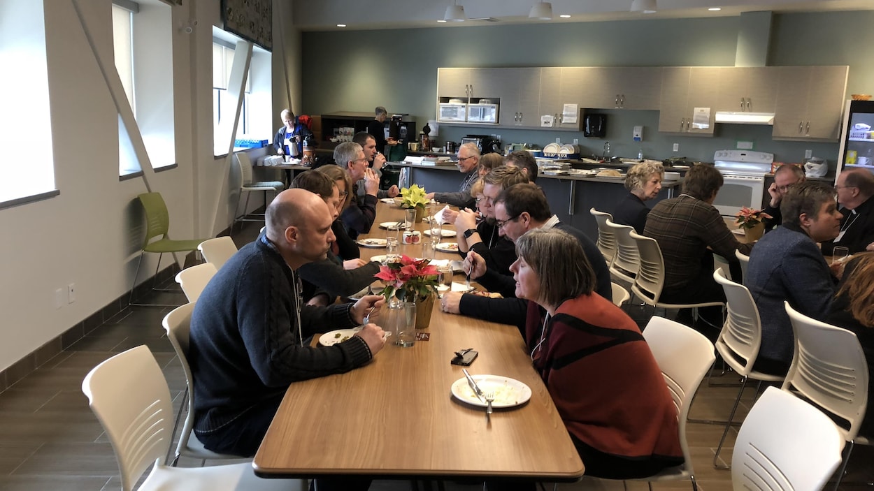 Des gens assis à une table parlent et mangent.