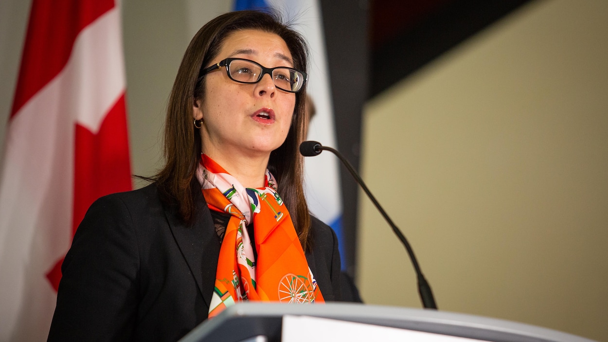 Une femme avec un foulard orange devant un podium.