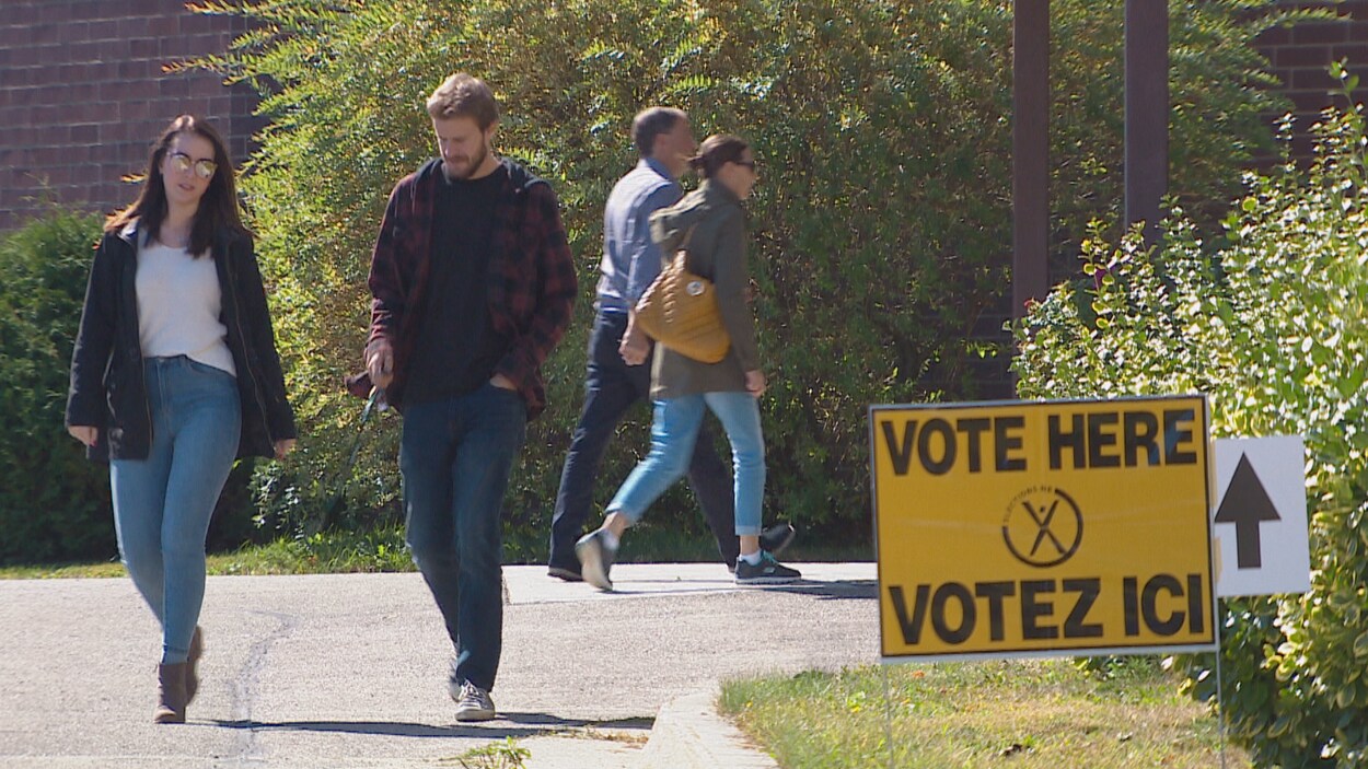 Des gens se rendent à un bureau de vote.