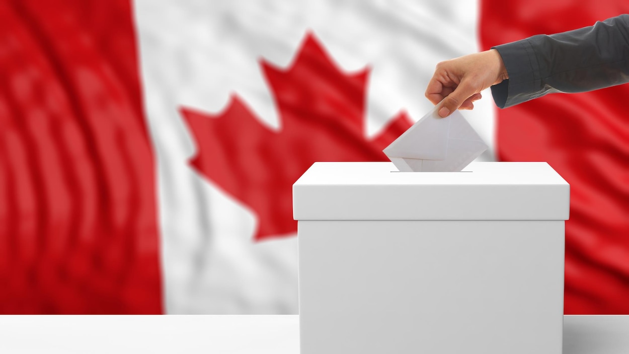 Une main dépose un bulletin de vote dans une boîte de scrutin.