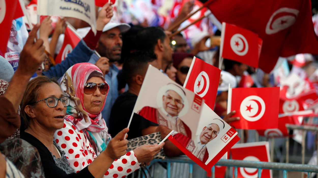 Une foule qui tient des drapeaux de la Tunisie et des affiches électorales.