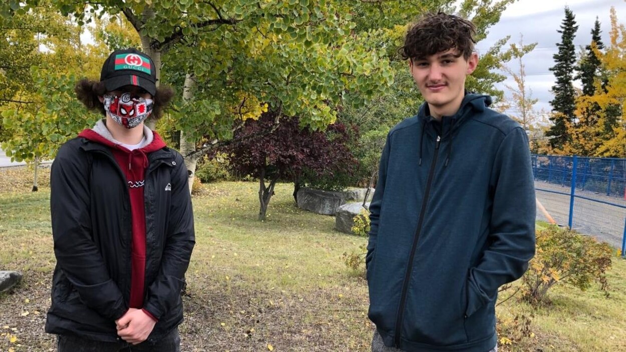 Deux jeunes dont celui de gauche porte un masque coloré et une casquette.