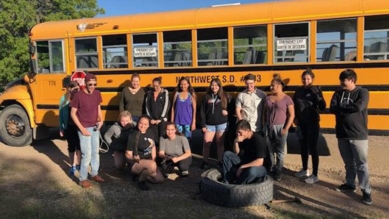Les élèves, dans l’adolescence, posent pour une photo près de l'autobus en panne.
