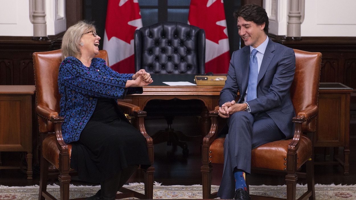 Elizabeth May rit et Justin Trudeau sourit dans le bureau du premier ministre.