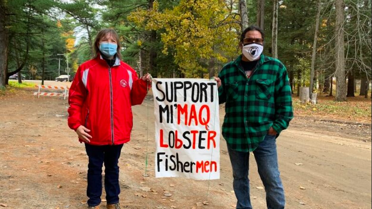 Ellen Gabriel et Al Harrington portent le masque et tiennent une affiche. Ils se trouvent dans la pinède entre Oka et Kanesatake.