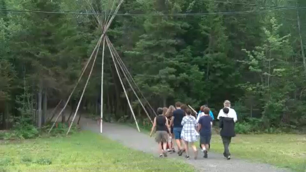 Une groupe de gens s'apprêtant à passé sous un tipi.