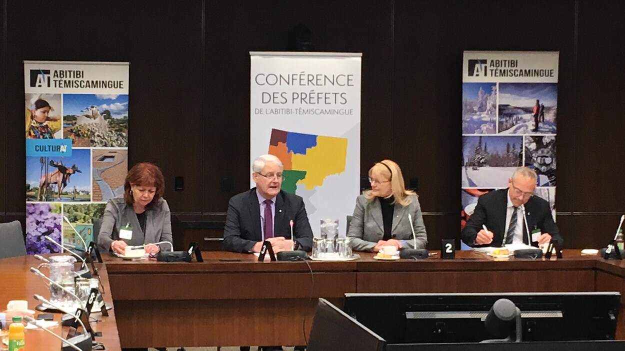 Diane Dallaire, Marc Garneau, Claire Bolduc et Sébastien D'Astous sont assis à une table de conférence devant des affiches représentant l'Abitibi-Témiscamingue.