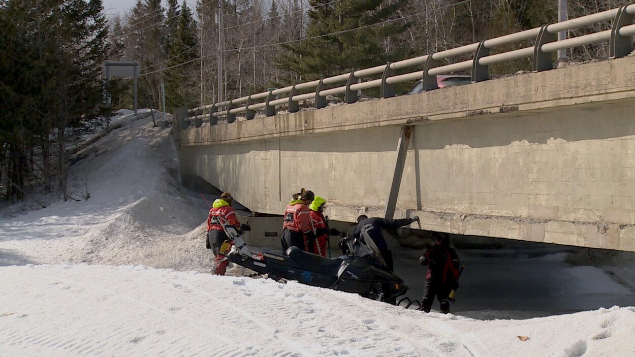Gens sur la glace observent un pont.
