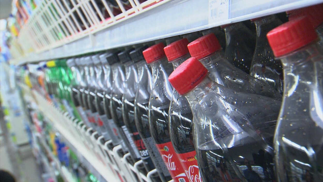 Des bouteilles de sodas dans un rayon d'épicerie.