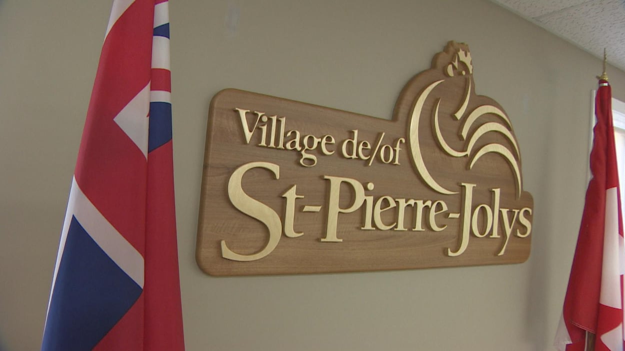 Photo de l'emblème du village de Saint-Pierre-Jolys, qui représente un coq stylisé, encadré par les drapeaux du Manitoba et du Canada.
