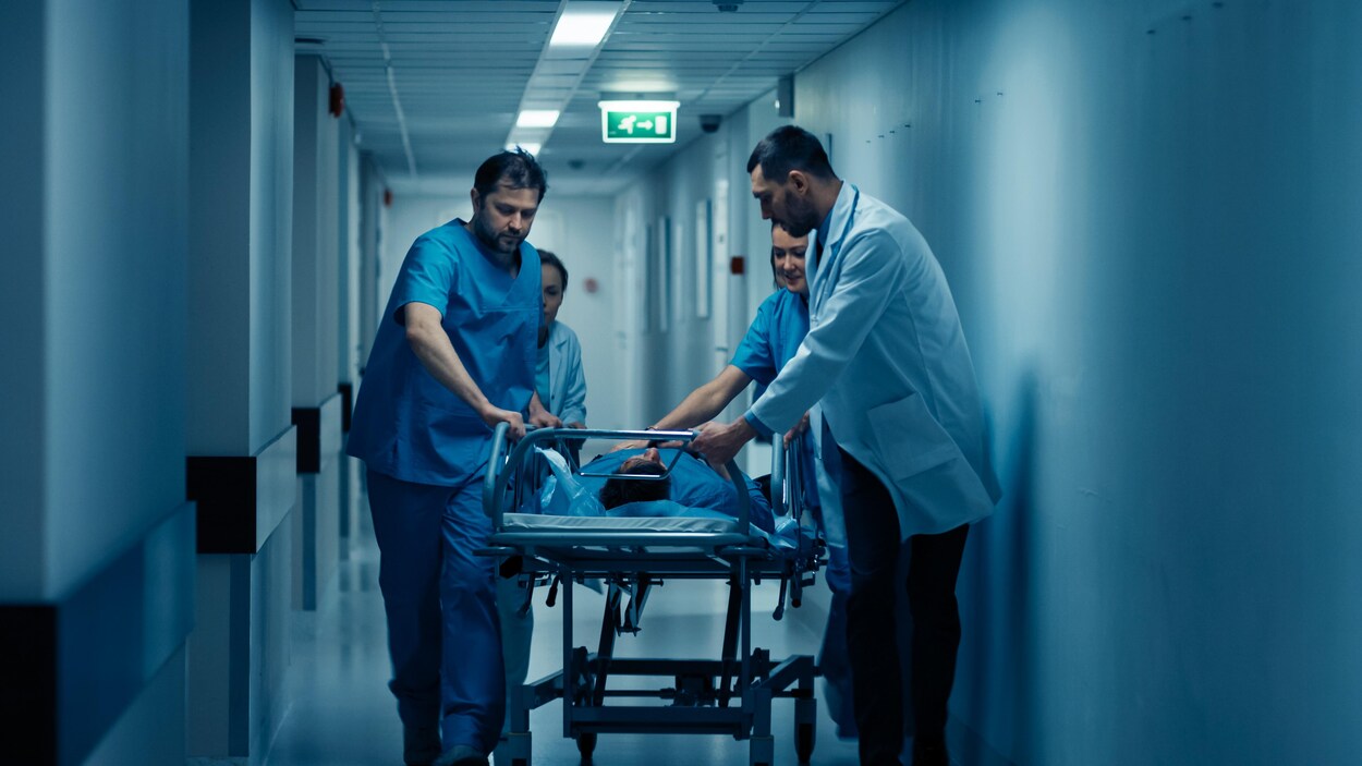 Des médecins transportent un patient en civière.