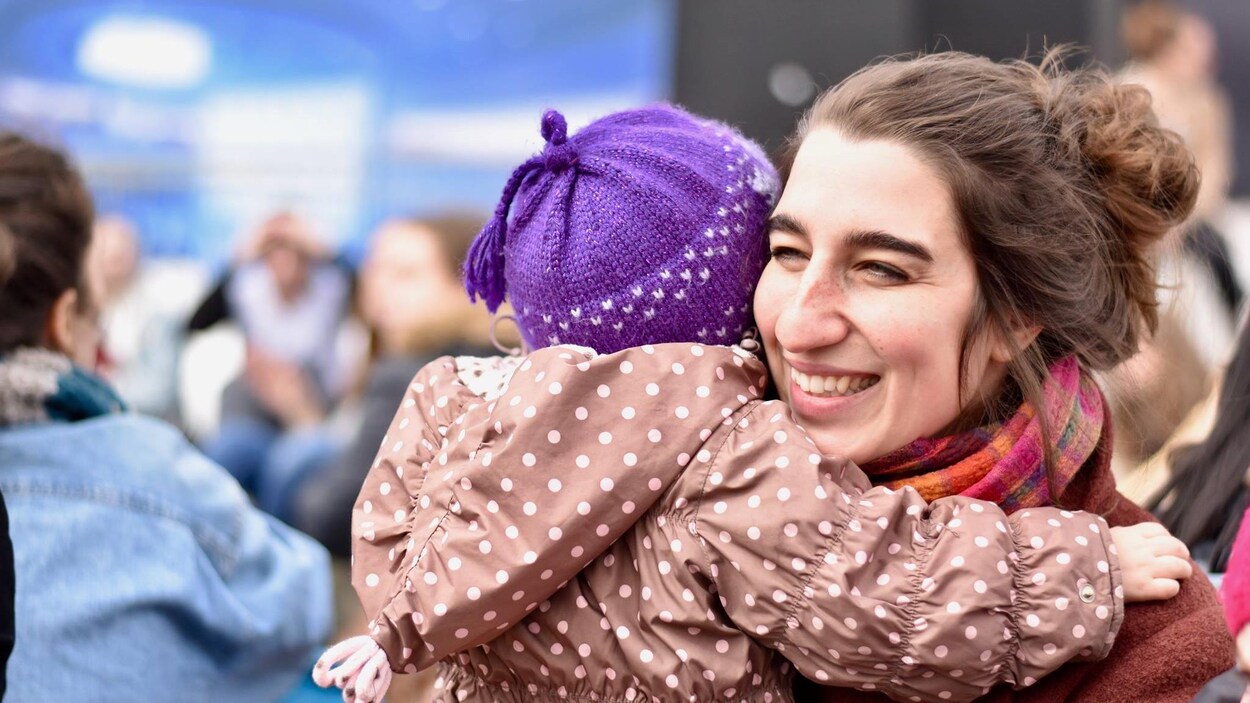 Émilise Lessard-Therrien serre dans ses bras un enfant qu'on voit de dos.