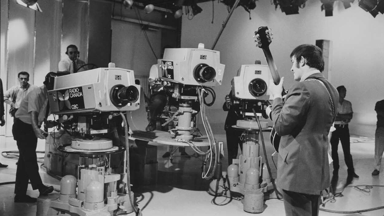 Trois caméras devant le guitariste Éric Nico, dans le studio de l'émission Zoom.