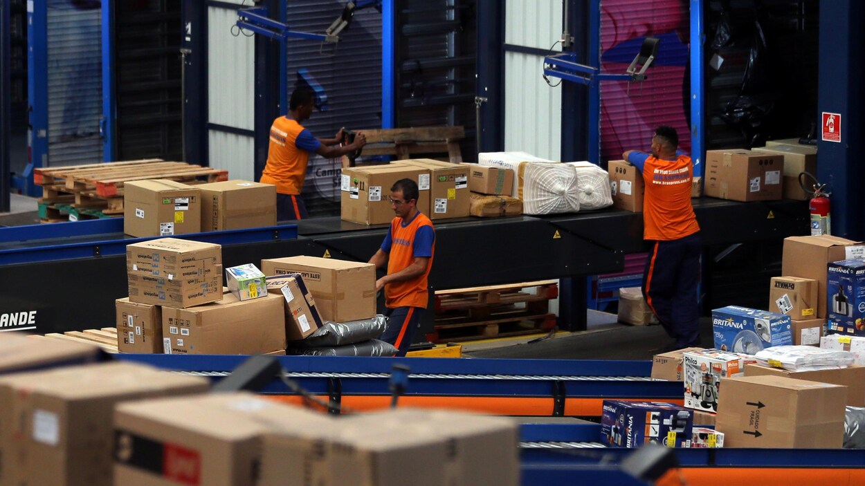 Des employés d’une entreprise de logistique manipulent des boîtes et préparent des commandes devant être expédiées.