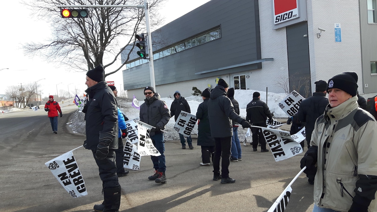 Des travailleurs munis de pancartes manifestent devant l'usine Sico Des travailleurs munis de pancartes manifestent devant l'usine Sico