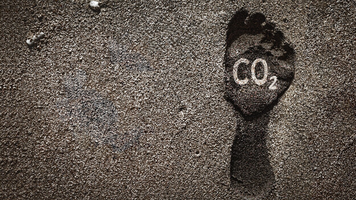 Marque laissée par un pied dans le sable, accompagnée par la formule chimique du gaz carbonique, représentant l'empreinte humaine sur le climat de la planète