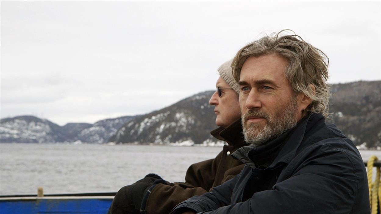 Deux hommes sur une embarcation regardent au loin.