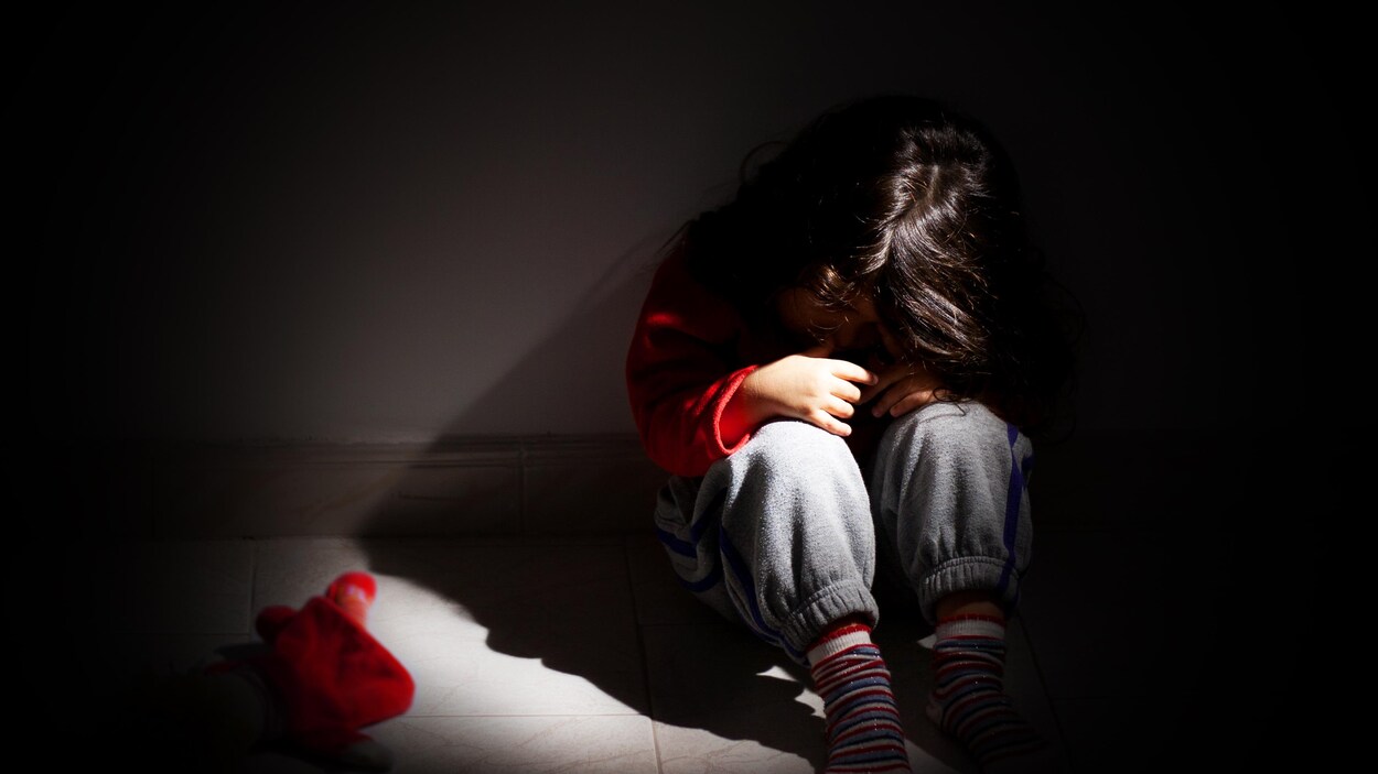 Jeune fille assise seule dans le noir.