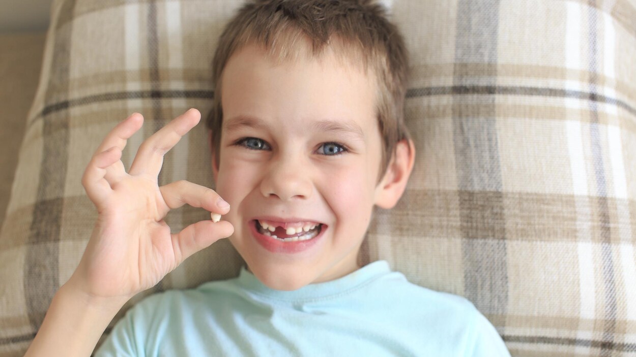 Un garçon se réjouit d'avoir perdu l'une de ses dents de bébé.
