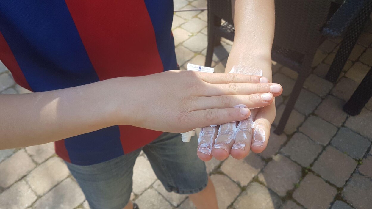 Gros plan de mains d'un enfant qui met de la crème à mains.