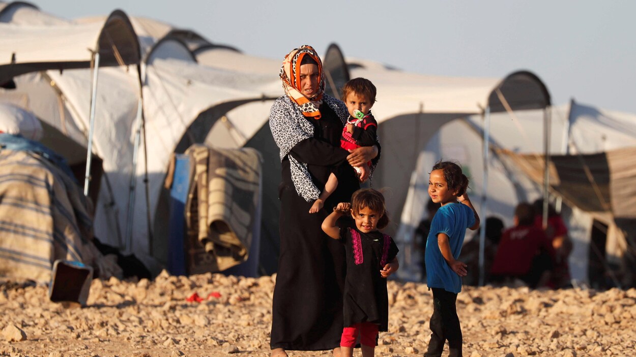 L'un des enfants est dans les bras de la femme, au centre de la photo. L'un des enfants est dans les bras de la femme, au centre de la photo.