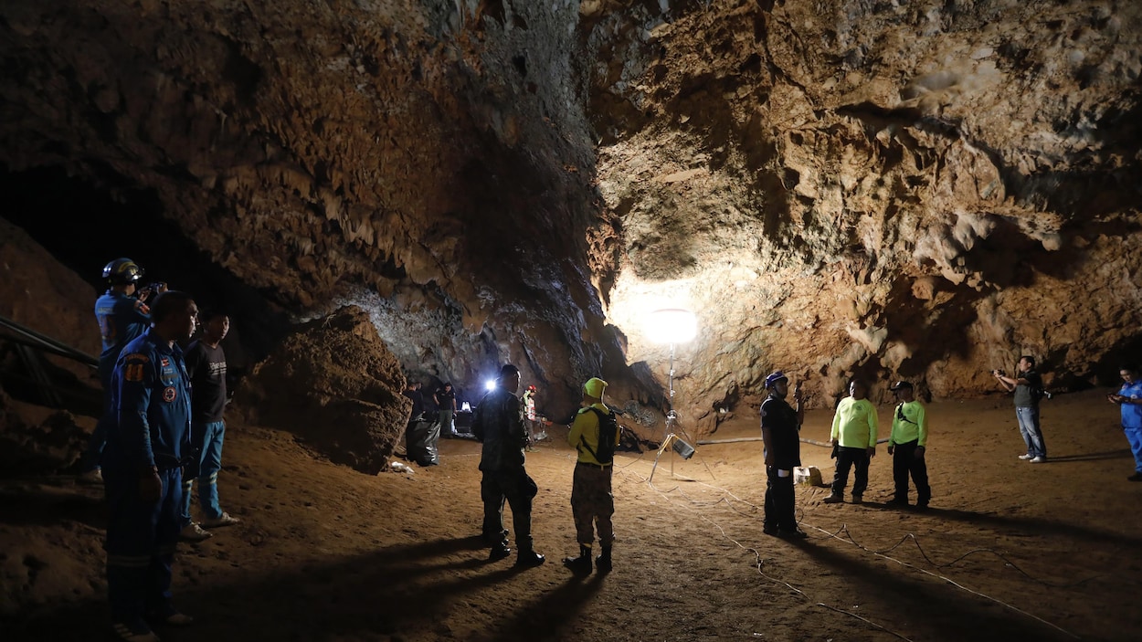 Une dizaine de personnes qui forment l'équipe de sauvetage se trouvent dans une grotte. Certains portent des lampes de poche. Une dizaine de personnes qui forment l'équipe de sauvetage se trouvent dans une grotte. Certains portent des lampes de poche.