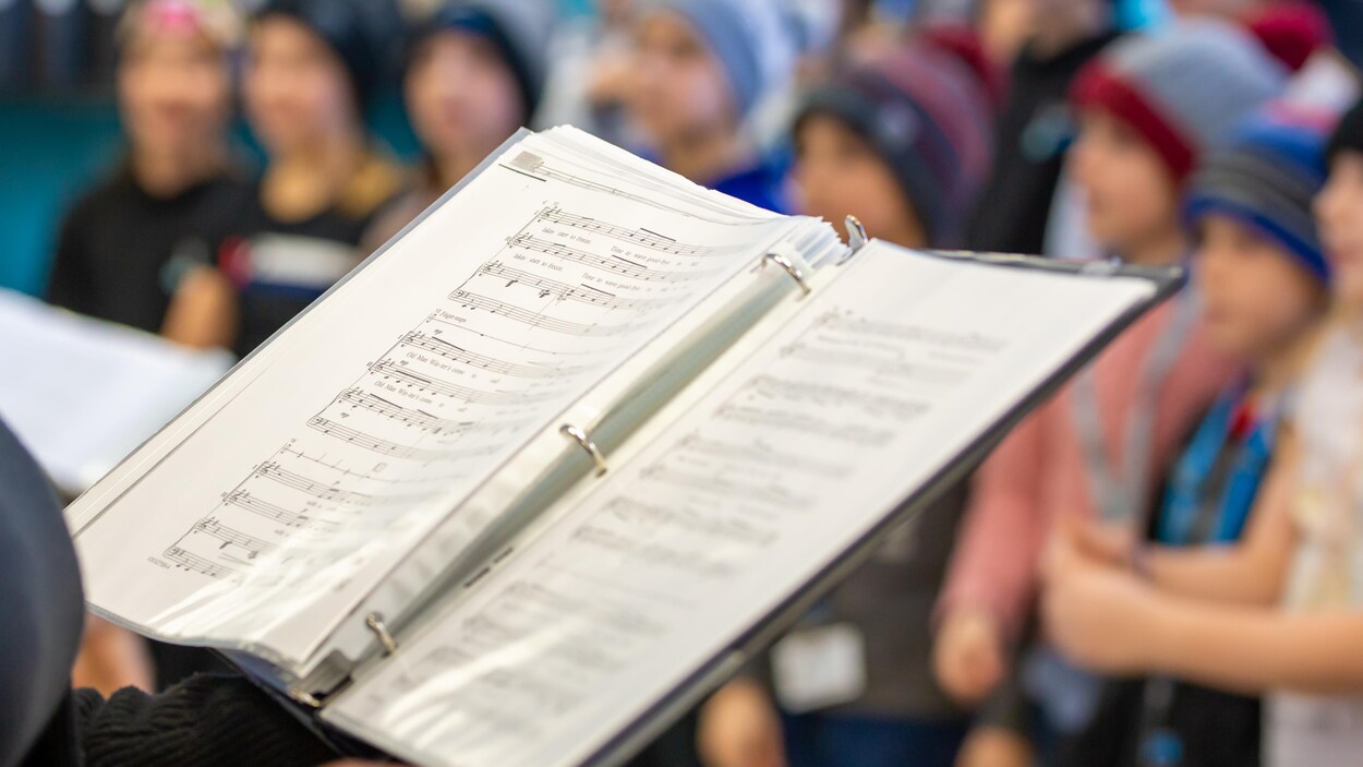 Une partition de musique, avec des enfants à l'arrière plan