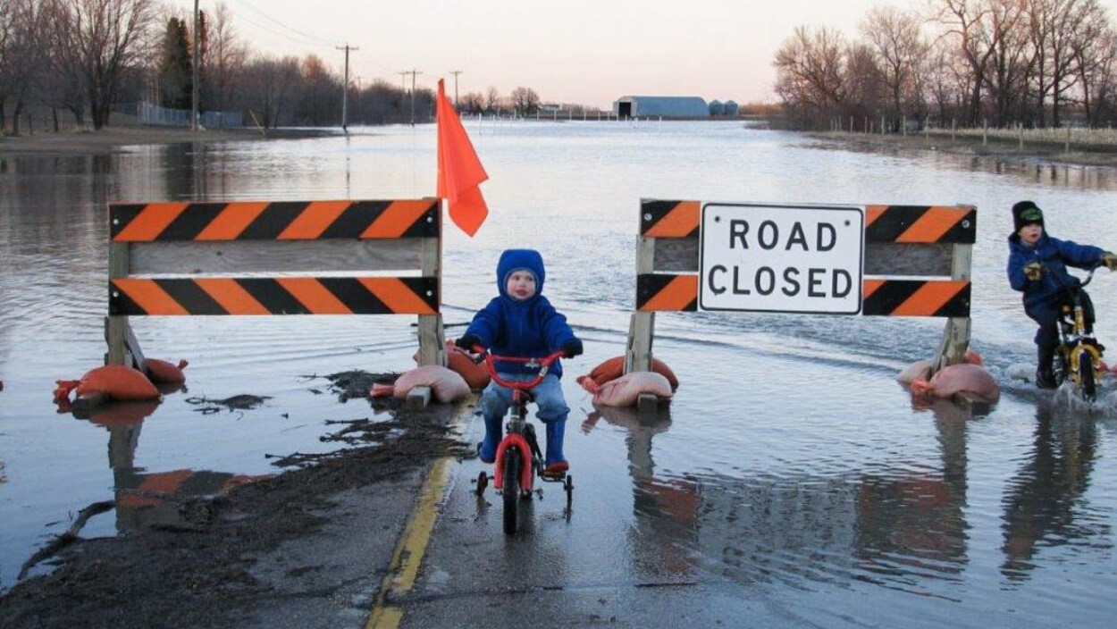 Des enfants à vélo dans une rue inondée