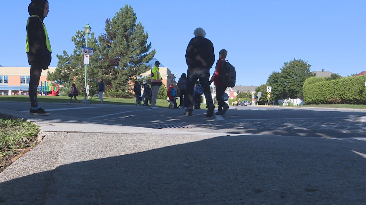 Des écoliers traversent la rue sous l’œil vigilant d'un brigadière.