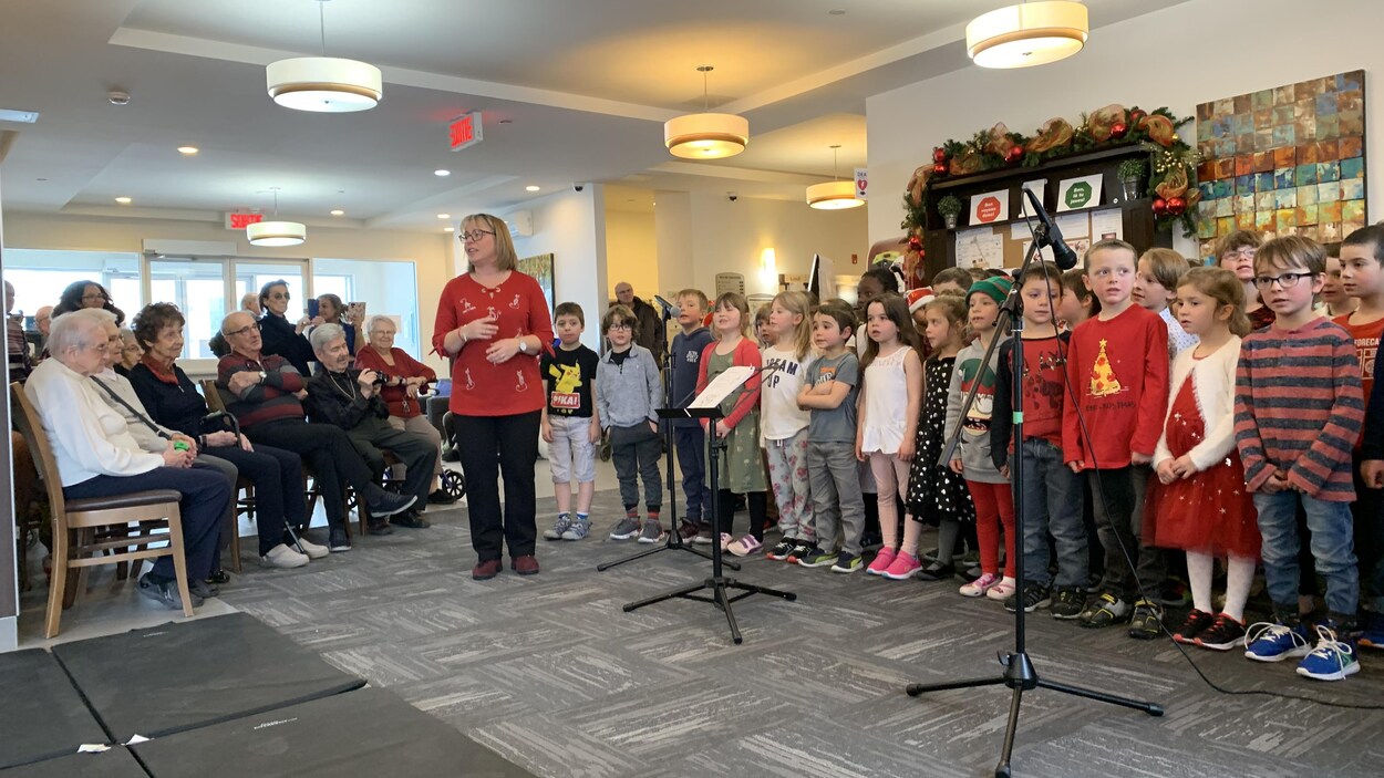 Une chorale d'enfants chante devant des personnes âgées.