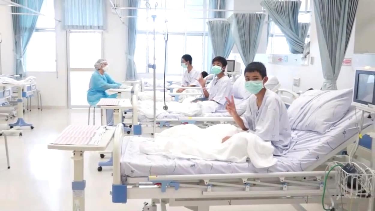 Trois des 12 garçons rescapés posent dans une chambre d'hôpital en Thaïlande.