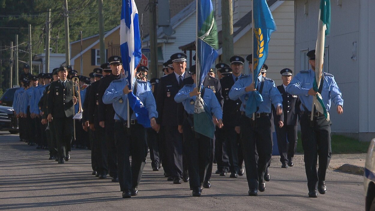 Gens qui défilent dans la rue en uniforme et des drapeaux.