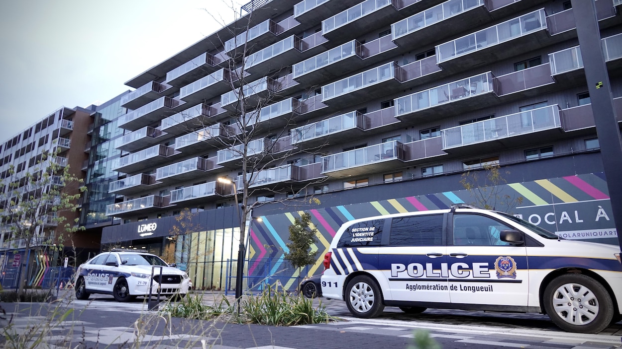 Deux voitures de la police stationnés au pied d'une barre d'immeubles.