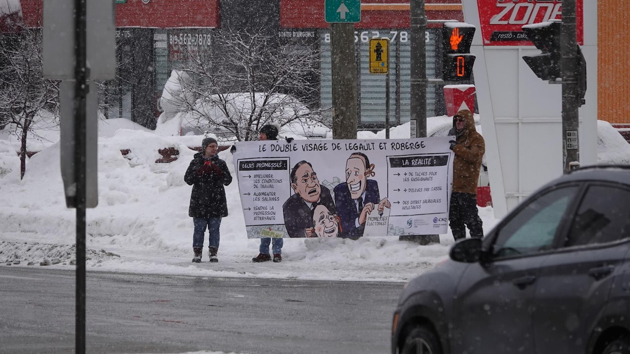 Des enseignants avec une banderole qui dénonce le gouvernement Legault.