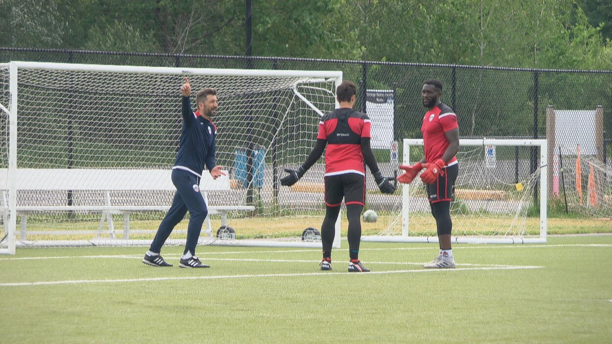 Trois joueurs de soccer discutent pendant un entraînement de l'Atlético d'Ottawa.