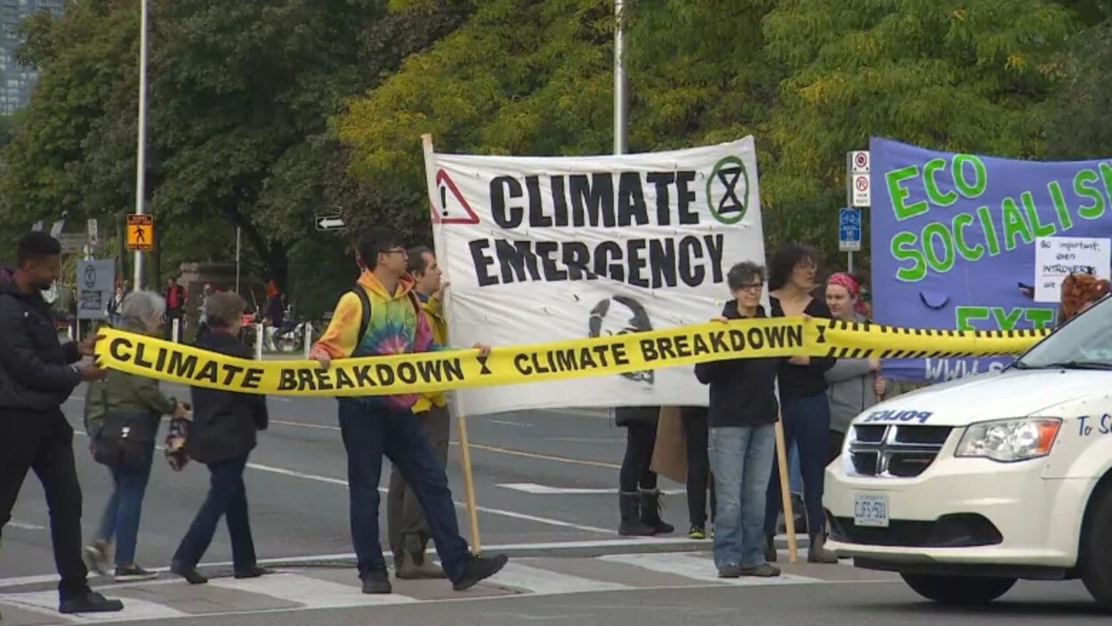 Des manifestants tenant des affiches sur l'urgence climatique dans la rue.