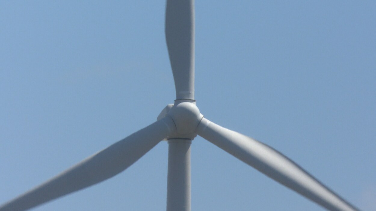Un gros plan sur une éolienne, dans un ciel bleu.