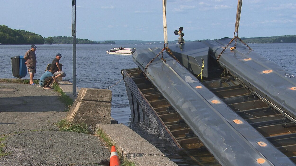 L'épave est maintenue par une grue aux abords du quai.