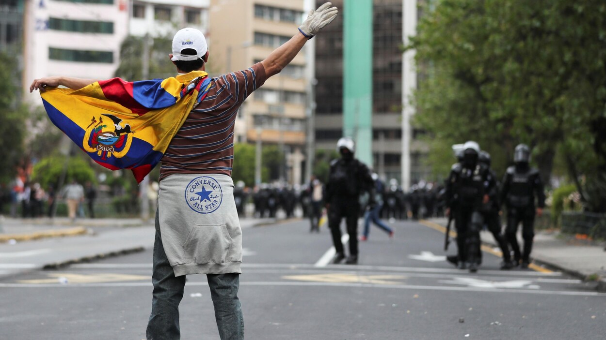 Un manifestant se tient devant des policiers à Quito vendredi.