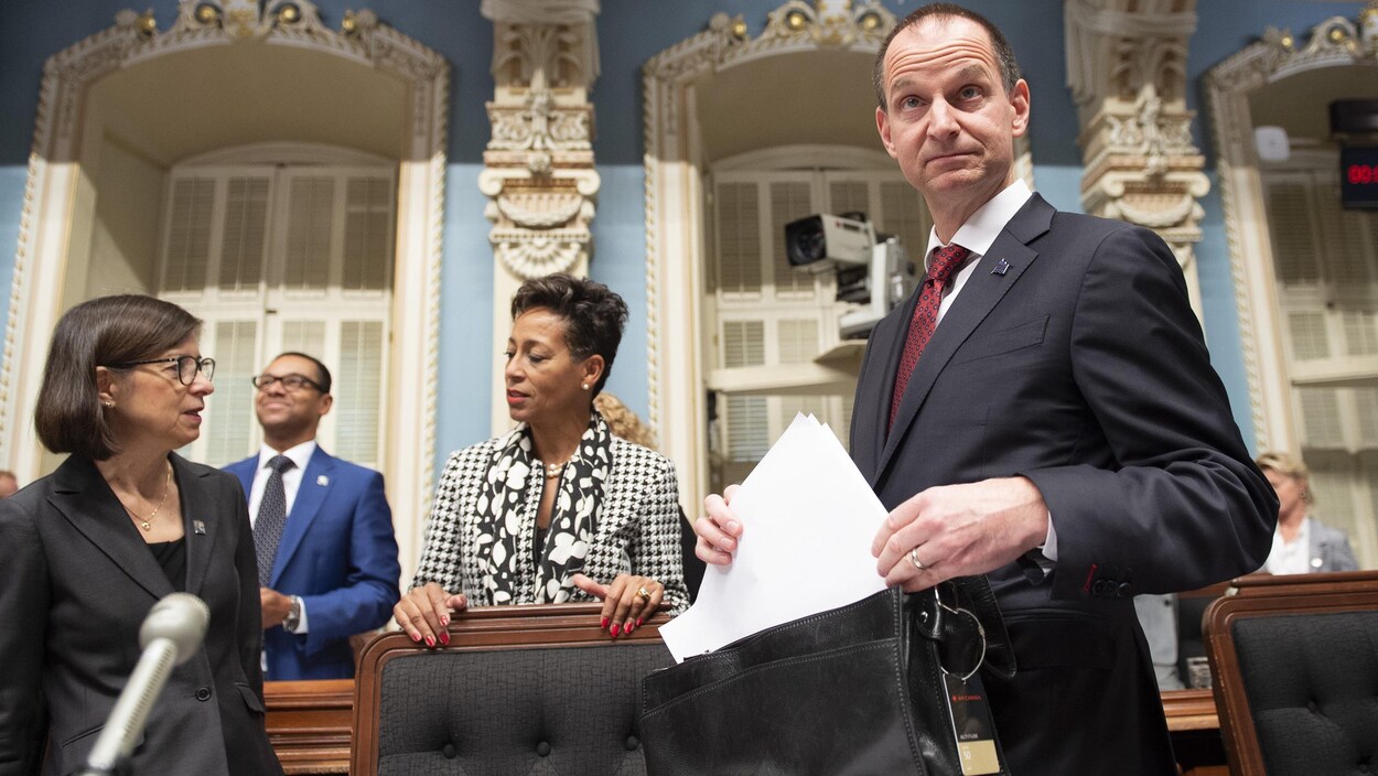 Eric Girard range des documents dans sa serviette au Salon bleu de l'Assemblée nationale.