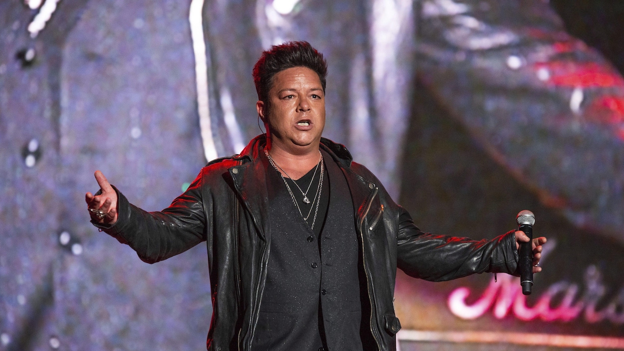 Le chanteur sur scène, micro à la main.