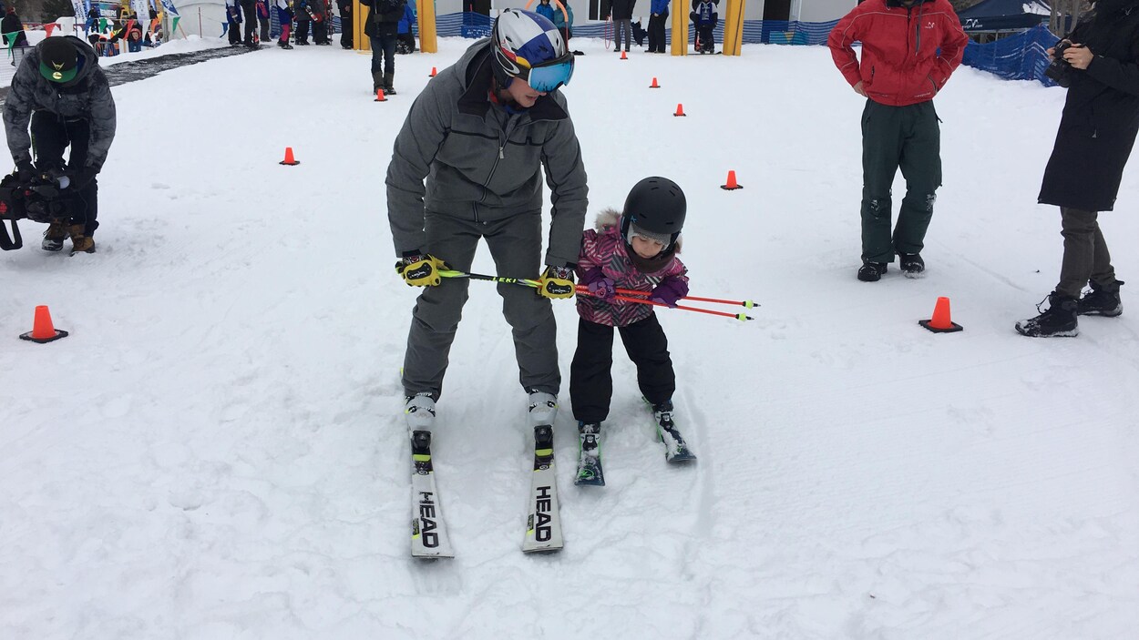 Un homme et une fille tiennent des bâtons de ski pour descendre une piste