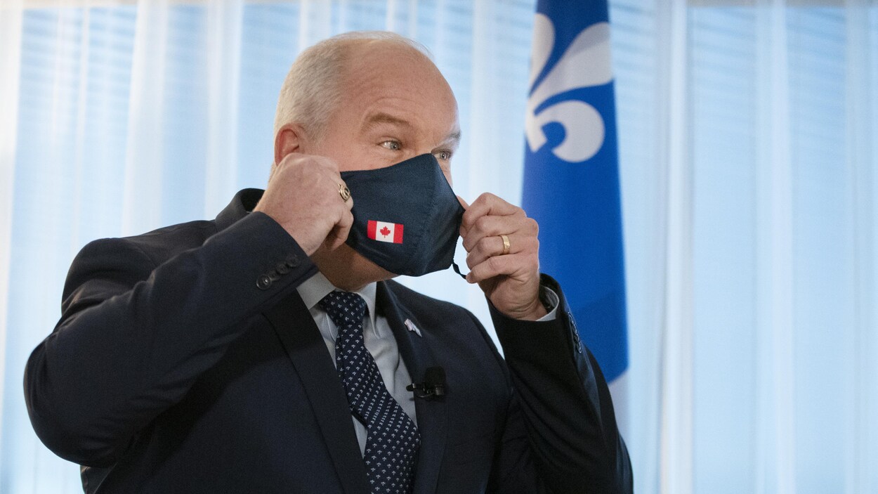 Le nouveau chef du Parti conservateur fédéral, Erin O’Toole, tient un masque devant son visage.