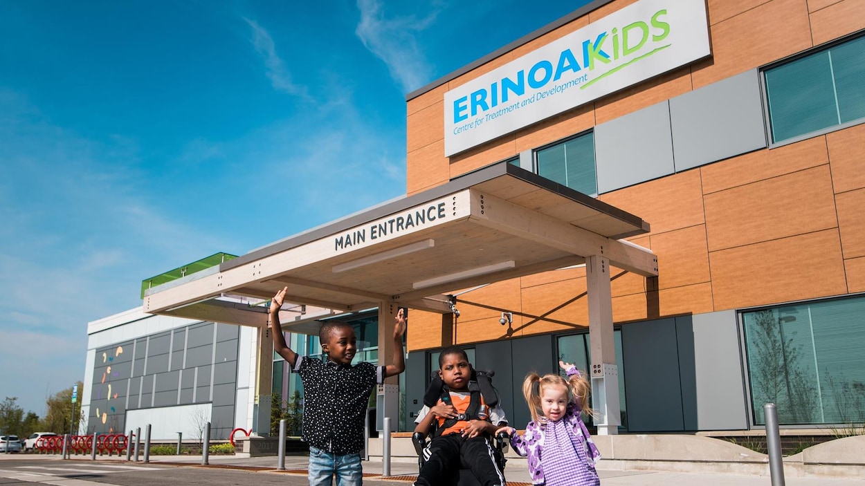 Trois enfants devant l'entrée principale du centre ErinoakKids.