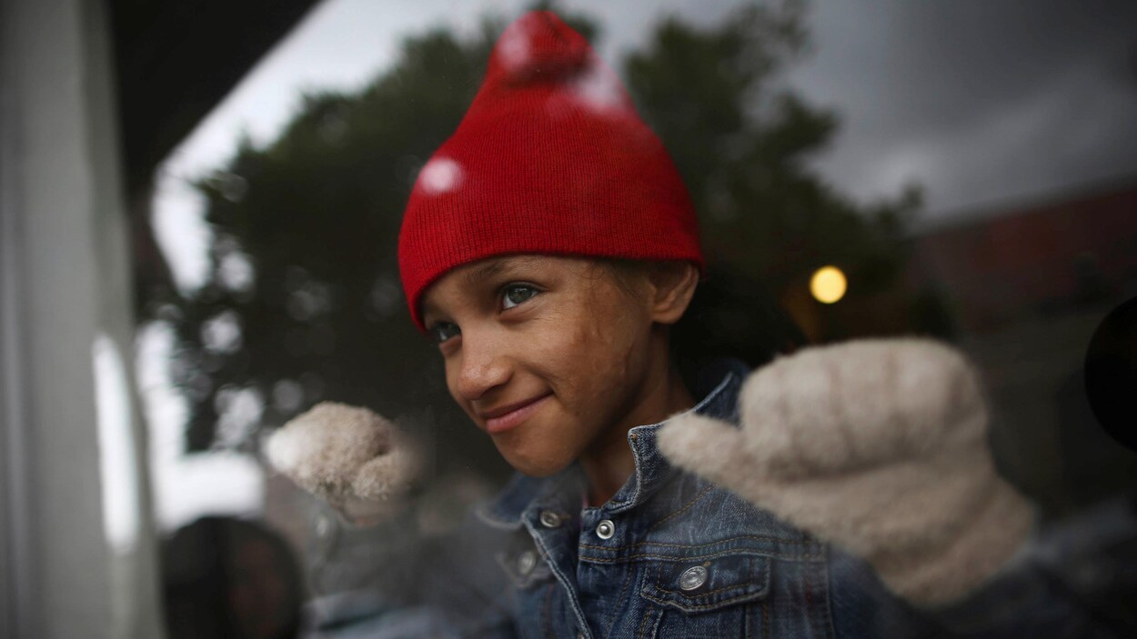 Une jeune fille regarde par une fenêtre.