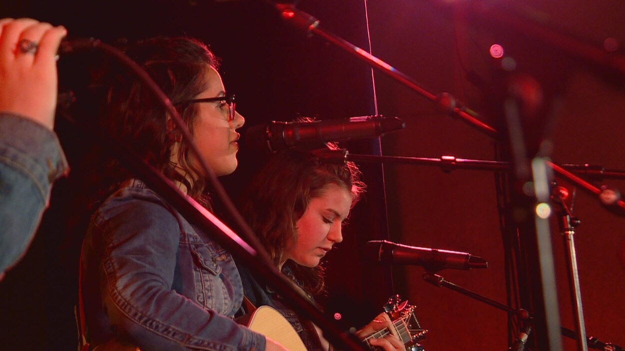 Deux jeunes filles de profil, devant des micros. Le groupe Étincelles, composée de sept musiciennes de Falher, en était à sa première participation à la Chicane albertaine. Deux jeunes filles de profil, devant des micros. Le groupe Étincelles, composée de sept musiciennes de Falher, en était à sa première participation à la Chicane albertaine.